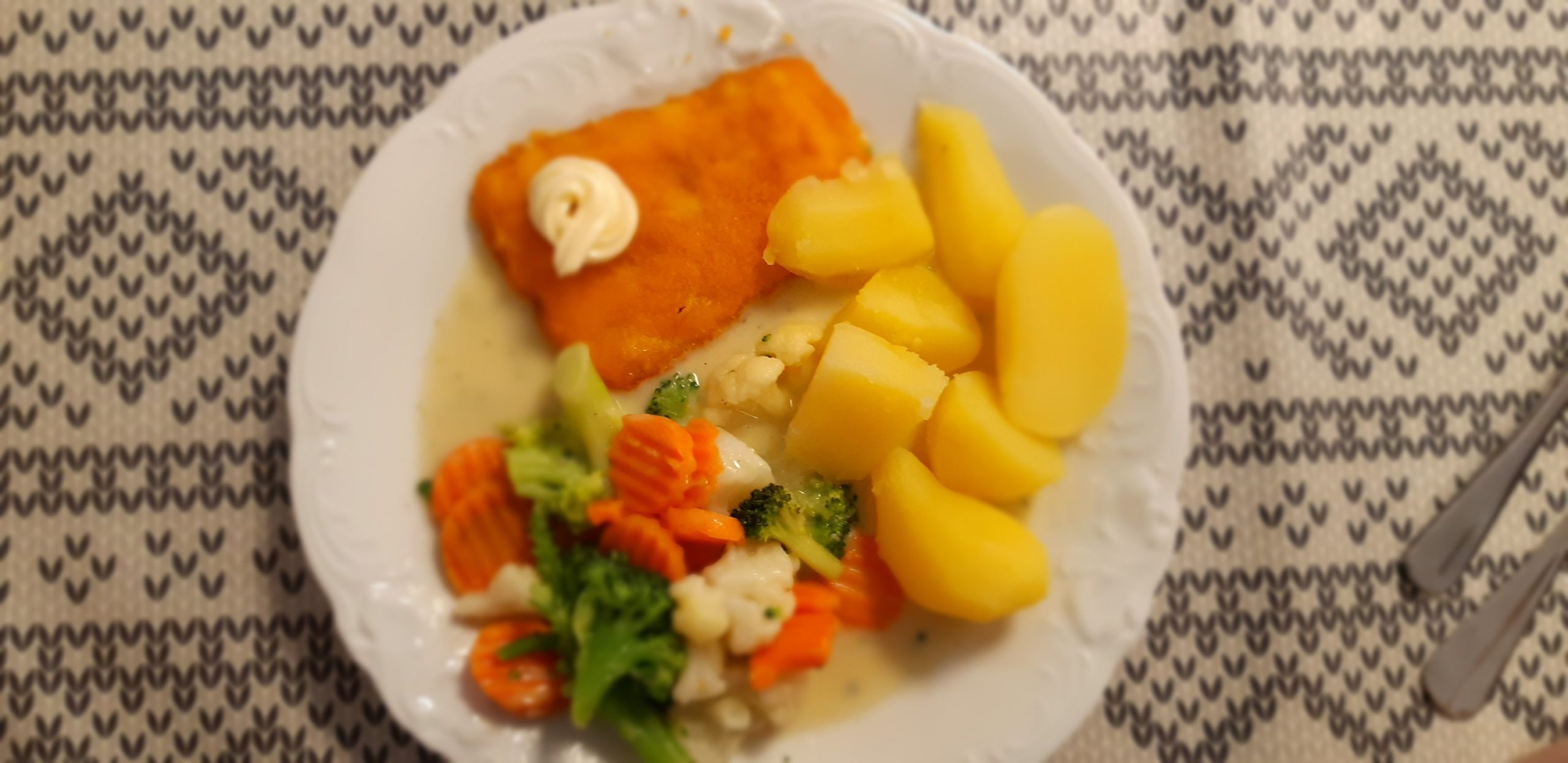 Teller mit Kartoffeln, Gemüse und Backfisch